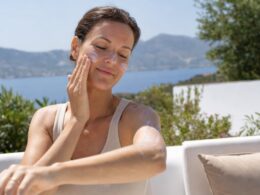 Frau cremt sich in der Sommersonne mit Sonnencreme ein