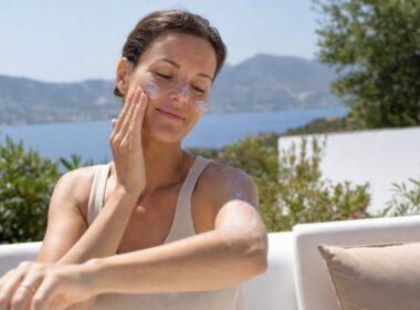 Frau cremt sich in der Sommersonne mit Sonnencreme ein