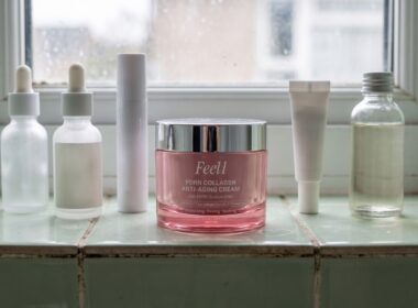 Six skincare jars and bottles in a row on a pale green tiled windowsill with a pink Feel1 PDRN cream jar in the center