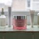 Six skincare jars and bottles in a row on a pale green tiled windowsill with a pink Feel1 PDRN cream jar in the center