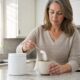 Woman in her mid-fifties stirring a scoop of white collagen powder into a coffee mug in a bright US kitchen